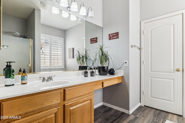 full bath featuring baseboards, vanity, walk in shower, and wood finished floors