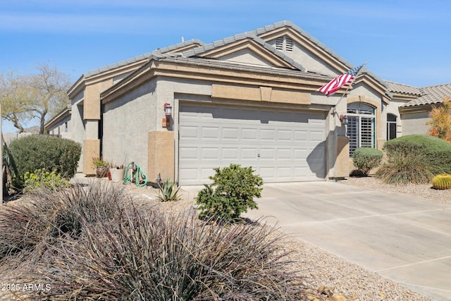 view of front of property with concrete driveway, a tiled roof, a garage, and stucco siding