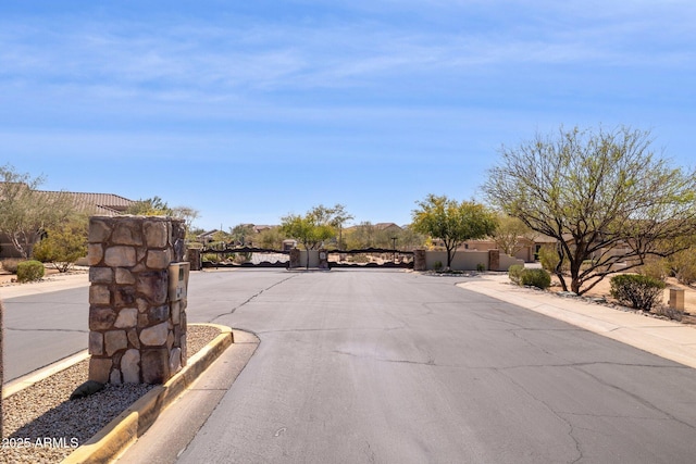 view of road with curbs, sidewalks, and a gated entry