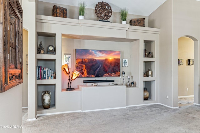 living area featuring built in features, baseboards, arched walkways, and carpet