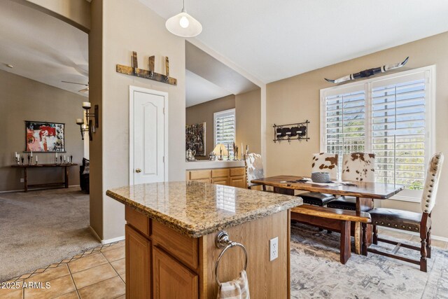 kitchen featuring light tile patterned floors, light colored carpet, a wealth of natural light, and a center island