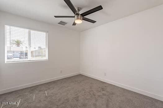 carpeted spare room featuring a ceiling fan and baseboards