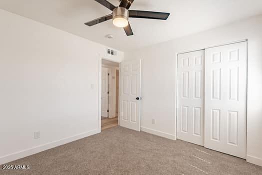 unfurnished bedroom with carpet flooring, baseboards, a closet, and ceiling fan