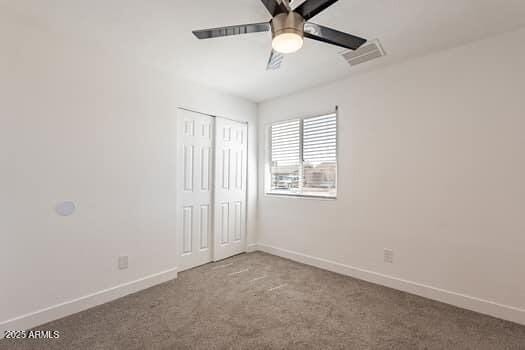 unfurnished bedroom featuring carpet, baseboards, a closet, and a ceiling fan