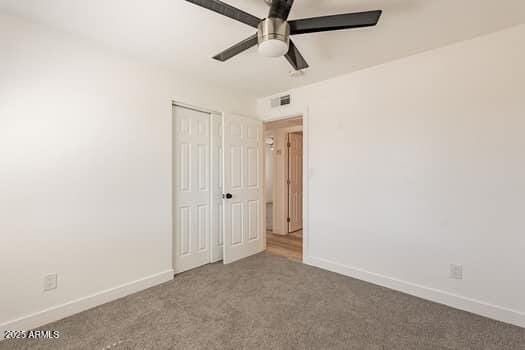 unfurnished bedroom with carpet, baseboards, a closet, and ceiling fan