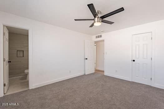 unfurnished bedroom with carpet flooring, baseboards, and ensuite bath