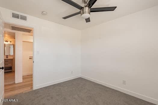 carpeted spare room featuring ceiling fan and baseboards