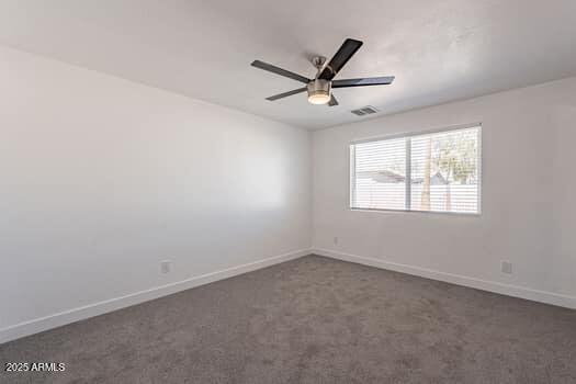 unfurnished room featuring dark carpet, ceiling fan, and baseboards