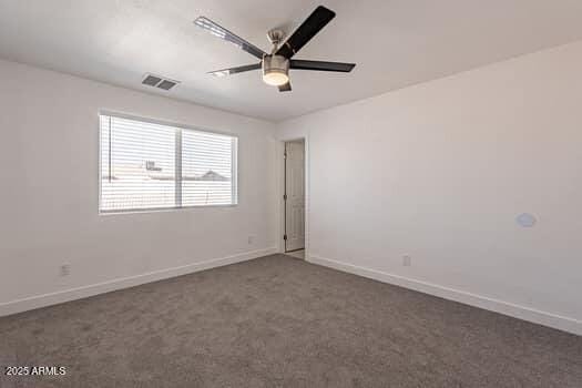 spare room featuring baseboards, ceiling fan, and dark carpet