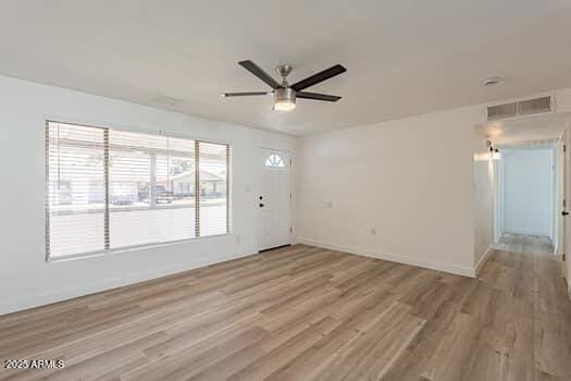 unfurnished living room featuring ceiling fan, light wood-style floors, and baseboards