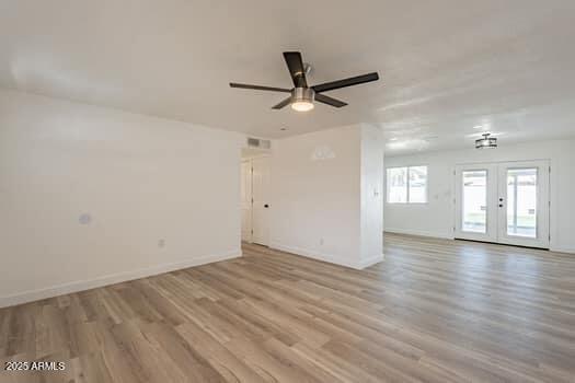 spare room with wood finished floors, a ceiling fan, baseboards, and french doors