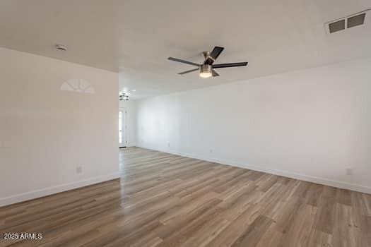 empty room featuring wood finished floors, ceiling fan, and baseboards