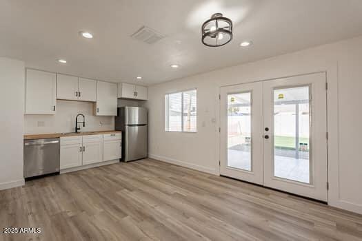 kitchen featuring appliances with stainless steel finishes, a sink, french doors, light wood finished floors, and recessed lighting