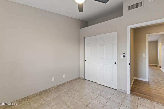 unfurnished bedroom with ceiling fan, light tile patterned flooring, and a closet