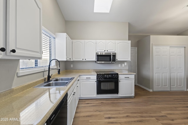 kitchen with a skylight, sink, white cabinets, and black appliances