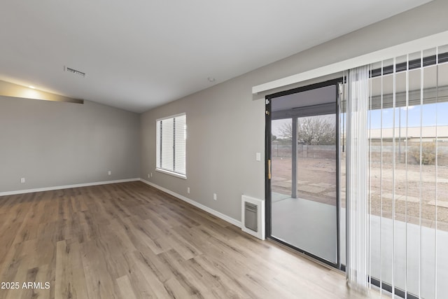 unfurnished room with plenty of natural light, lofted ceiling, and hardwood / wood-style flooring