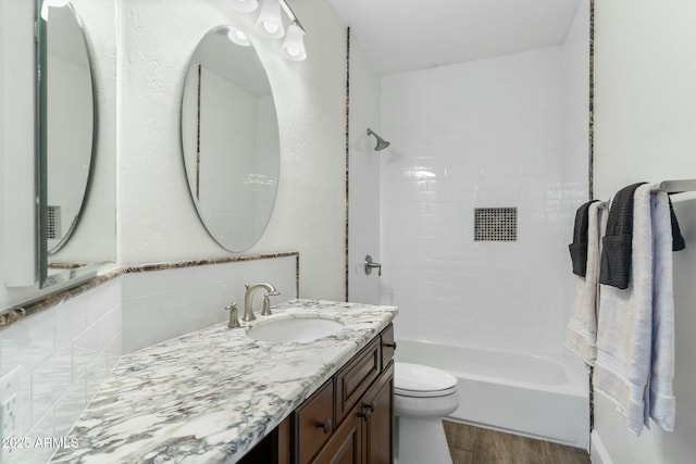 full bathroom with vanity, wood-type flooring, tiled shower / bath, and toilet