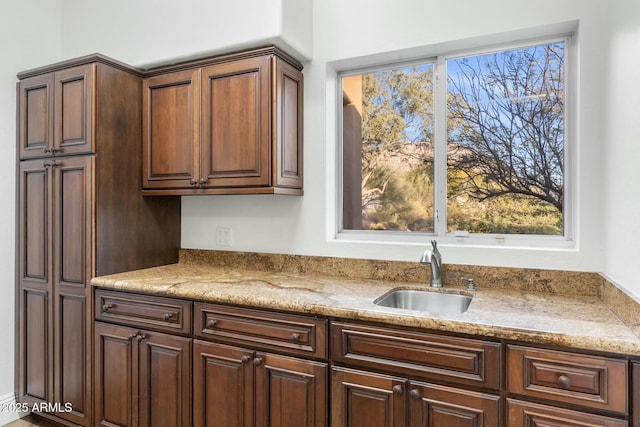 kitchen featuring light stone counters and sink