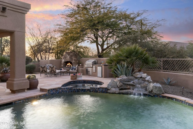 pool at dusk featuring a patio, pool water feature, area for grilling, and exterior fireplace