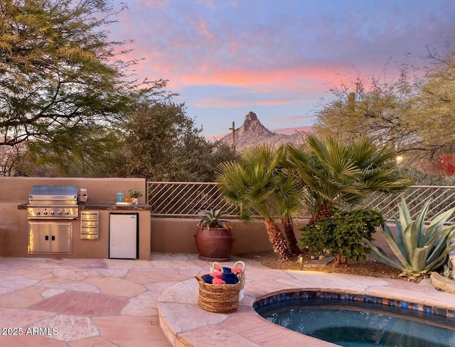 patio terrace at dusk with a grill and exterior kitchen