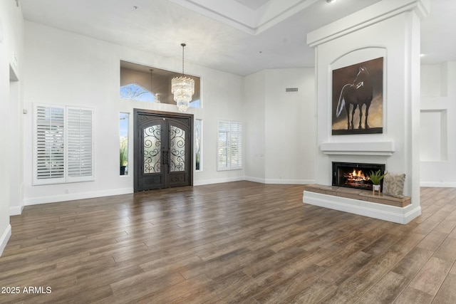 entryway featuring an inviting chandelier, a towering ceiling, dark wood-type flooring, and french doors