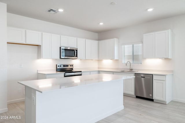 kitchen featuring light hardwood / wood-style floors, stainless steel appliances, a kitchen island, sink, and white cabinetry