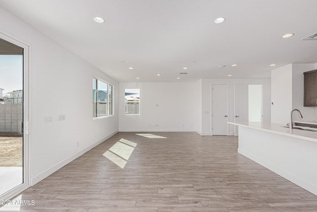 unfurnished living room featuring light hardwood / wood-style floors and sink