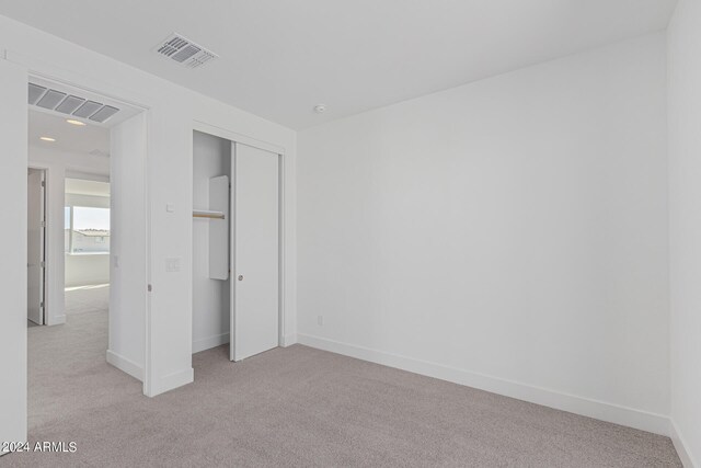 unfurnished bedroom with a closet and light colored carpet