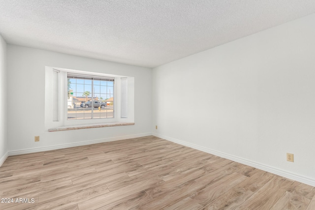 unfurnished room with a textured ceiling and light hardwood / wood-style floors