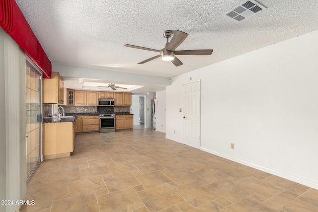 kitchen featuring appliances with stainless steel finishes, backsplash, a textured ceiling, and ceiling fan