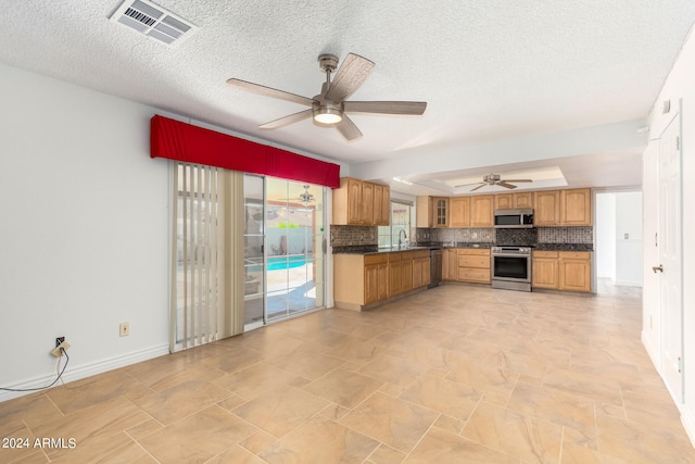 kitchen featuring a textured ceiling, sink, decorative backsplash, stainless steel appliances, and ceiling fan