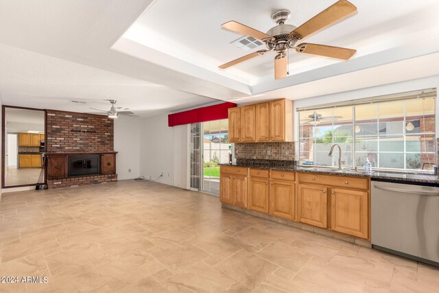 kitchen with dishwasher, sink, a fireplace, decorative backsplash, and ceiling fan