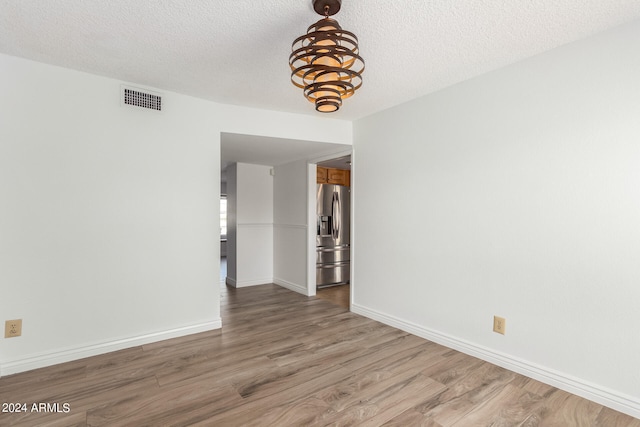 empty room featuring a textured ceiling and wood-type flooring