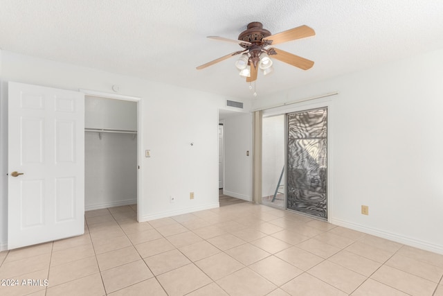 unfurnished bedroom with a textured ceiling, light tile patterned floors, ceiling fan, and a closet