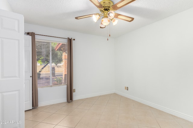 spare room with a textured ceiling, light tile patterned floors, and ceiling fan