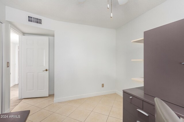 unfurnished bedroom featuring ceiling fan, a textured ceiling, and light tile patterned flooring