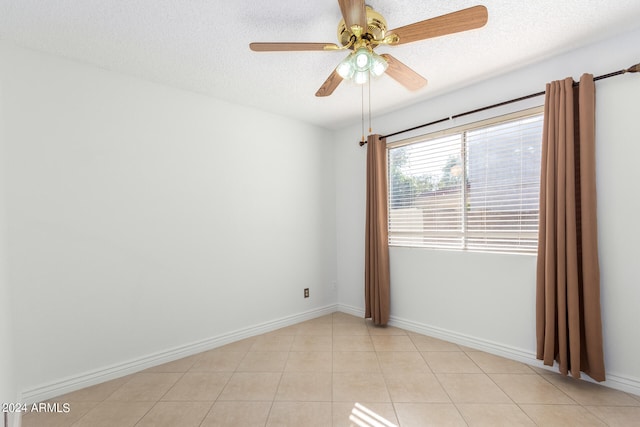 spare room featuring a textured ceiling, light tile patterned floors, and ceiling fan