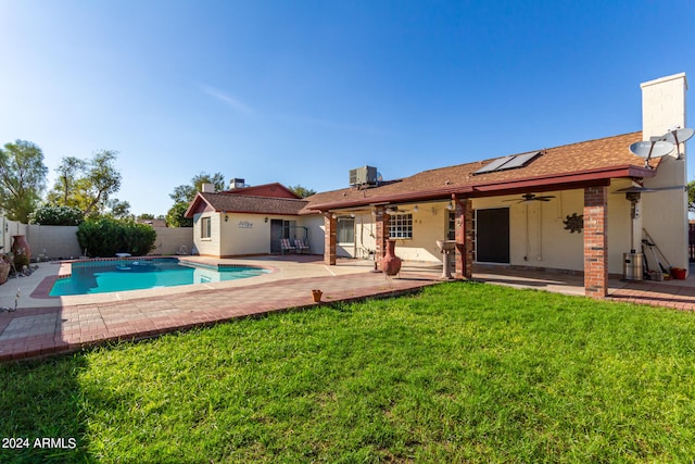 rear view of house with a yard, a fenced in pool, cooling unit, ceiling fan, and a patio area