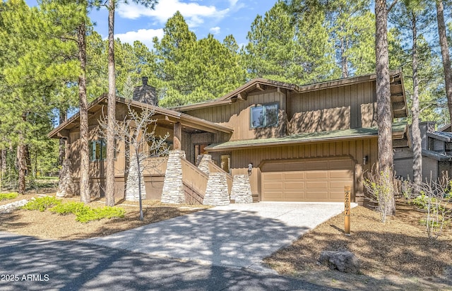 view of front of house featuring an attached garage, a chimney, stone siding, driveway, and stairway