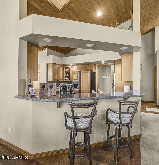 kitchen featuring paneled built in refrigerator, brown cabinetry, wood ceiling, a peninsula, and baseboards