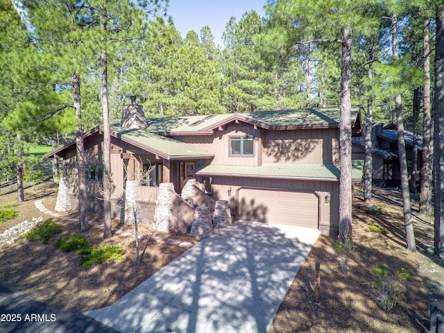 view of front of home featuring covered porch, driveway, a chimney, and a garage