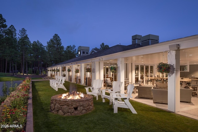rear view of house with a yard, a patio, and an outdoor living space with a fire pit