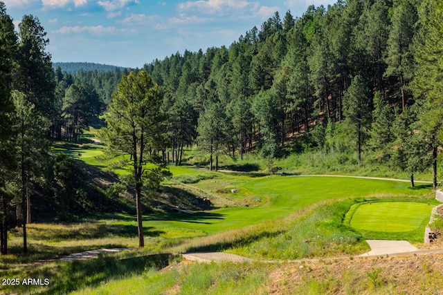 view of property's community with view of golf course and a view of trees