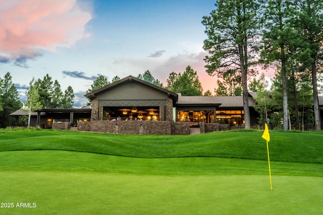 back of house with an area to practice putting, a yard, and golf course view