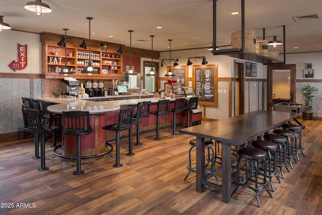 indoor wet bar featuring wainscoting, wood finished floors, recessed lighting, and hanging light fixtures