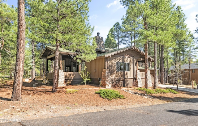 chalet / cabin featuring a chimney and covered porch