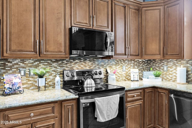 kitchen featuring stainless steel appliances, light stone countertops, and backsplash