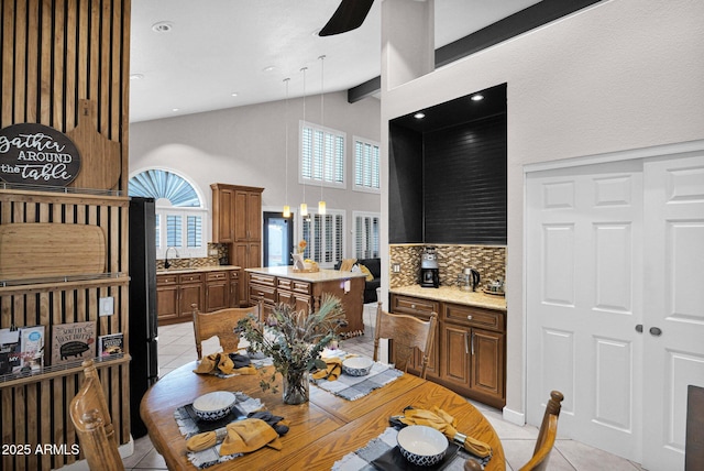 dining space with high vaulted ceiling, beamed ceiling, sink, light tile patterned floors, and ceiling fan