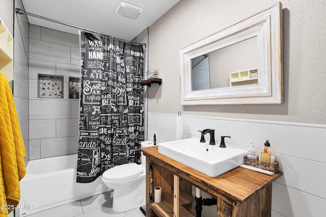 full bathroom featuring shower / tub combo with curtain, sink, tile patterned flooring, tile walls, and toilet