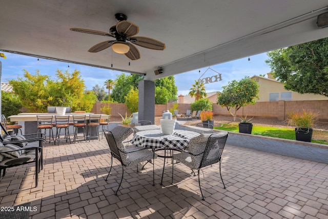 view of patio with ceiling fan and a bar